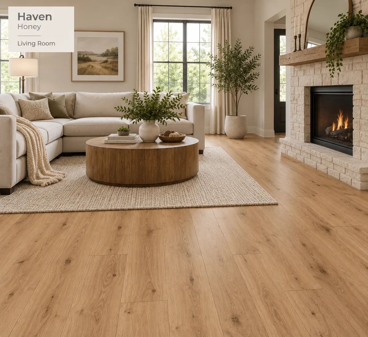 Living room with a white sectional, a round wood coffee table and a stone fireplace on Haven Honey laminate