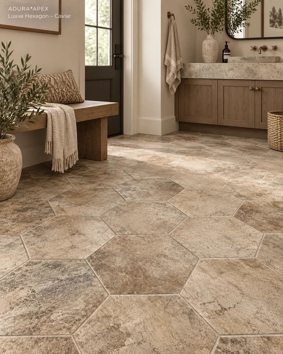 Bathroom with a wood bench and a vanity with a stone sink on tan stone-look Luxxe Hexagon Caviar tiles